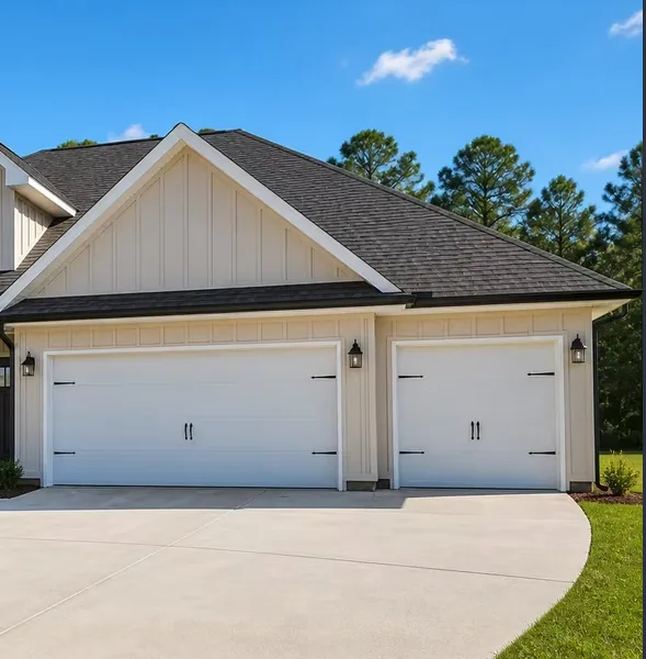 Cream gutters along the garage eaves of a board-and-batten farmhouse-style home with two white garage doors